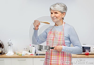 senior woman in apron with pot cooking food Stock Photo