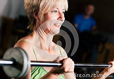 Senior Woman with barbell in gym Stock Photo