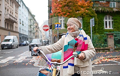 Senior woman with bicycle crossing road outdoors in city. Stock Photo