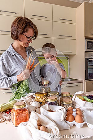 Senior woman brought in cloth bags of vegetables and cereals in glass jars from farmer market Stock Photo