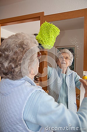 Senior woman cleaning mirror at home Stock Photo