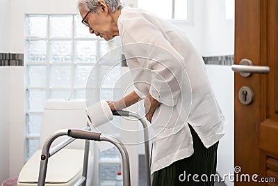 Senior woman with diarrhea holding tissue roll near a toilet bowl,elderly have abdominal pain,stomach ache,constipation in Stock Photo