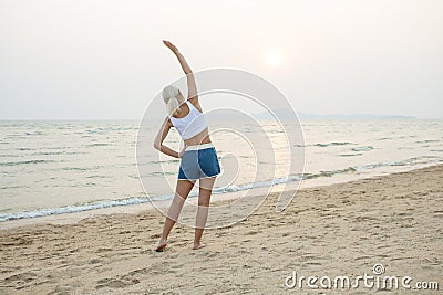attractive sporty woman doing stretching on beach Stock Photo