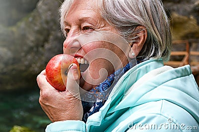 Senior woman eating apple outside in the park Stock Photo