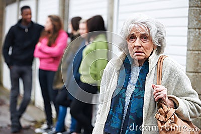 Senior Woman Feeling Intimidated By Group Of Young People Stock Photo