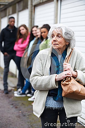 Senior Woman Feeling Intimidated By Group Of Young People Stock Photo