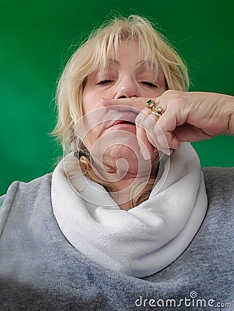 Senior woman with finger under nose - runny nose or sneeze - touching face - sick - green screen background Stock Photo