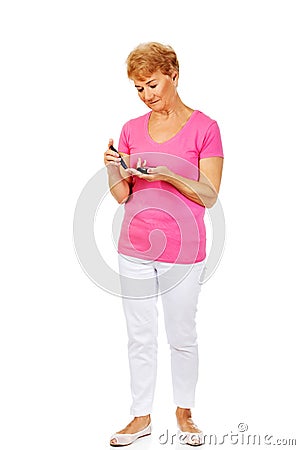 Senior woman with glucometer checking blood sugar level Stock Photo