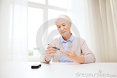 Senior woman with glucometer checking blood sugar Stock Photo