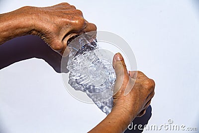 Senior woman hands squashing used plastic bottle, Water drops on transparent soft drink, White background, Global warming, Recycle Stock Photo