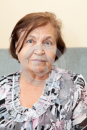 Senior woman head and shoulders indoors portrait, calm Caucasian person looking at camera Stock Photo