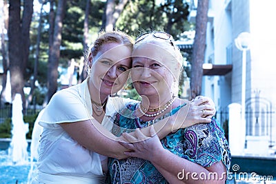 Senior woman and her daughter spending time together in the city park. elderly mom and daughter smile and hug happily Stock Photo