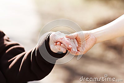 Senior woman holding hands with young caretaker Stock Photo