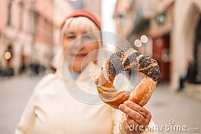 Senior woman holding prezel, traditional polish snack on the Market square in Krakow Stock Photo