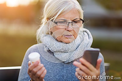 Woman holding smartphone and pill bottle Stock Photo