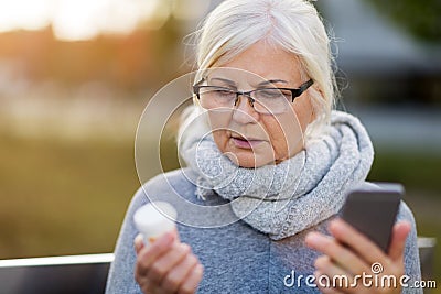 Woman holding smartphone and pill bottle Stock Photo