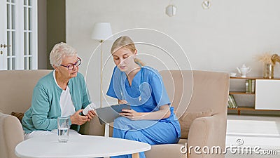 Senior woman holds bottle of pills listening to doctor advice at appointment in light office Stock Photo