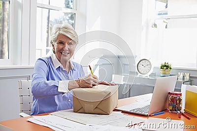 Senior Woman At Home Addressing Package For Mailing Stock Photo