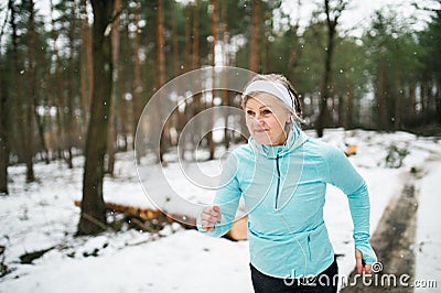 Senior woman jogging in winter nature. Stock Photo