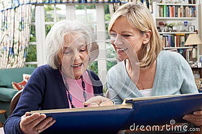 Senior Woman Looks At Photo Album With Mature Female Neighbor Stock Photo