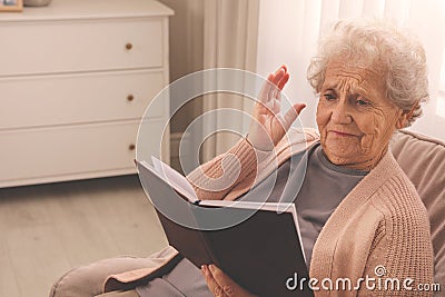 Senior woman with notebook at home, space for text. Age-related memory impairment Stock Photo