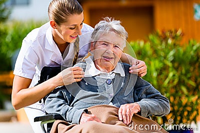 Senior woman in nursing home with nurse in garden Stock Photo