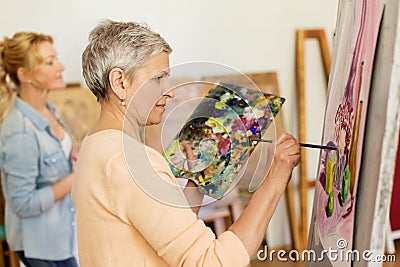 Senior woman painting at art school studio Stock Photo