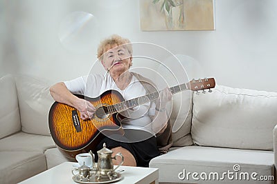 Senior woman playing the guitar Stock Photo