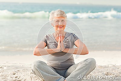 Senior woman practicing yoga on the beach Stock Photo