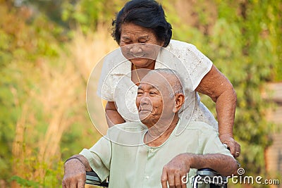 Senior woman pushing her disabled husband Stock Photo