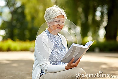 Senior woman reading book at summer park Stock Photo