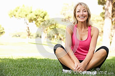 Senior Woman Resting After Exercising In Park Stock Photo