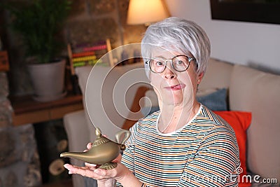 Senior woman rubbing genie lamp Stock Photo