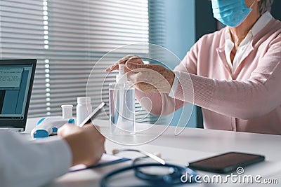 Senior woman sanitizing her hands at the doctor`s office Stock Photo