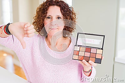 Senior woman showing nudes eyeshadows colors with angry face, negative sign showing dislike with thumbs down, rejection concept Stock Photo