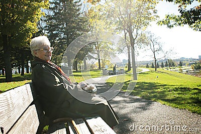Senior woman sit on a bench Stock Photo