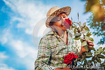 Senior woman smelling flowers in garden. Elderly retired woman enjoying hobby Stock Photo