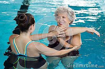 Senior woman stretching in pool Stock Photo