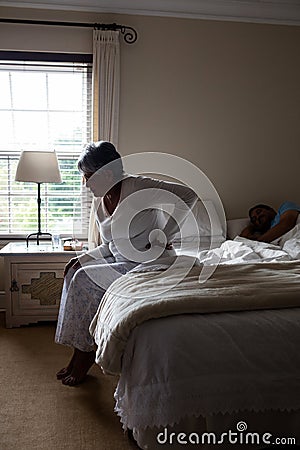 Senior woman suffering from back pain while sitting on bed Stock Photo