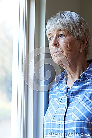 Senior Woman Suffering From Depression Looking Out Of Window Stock Photo