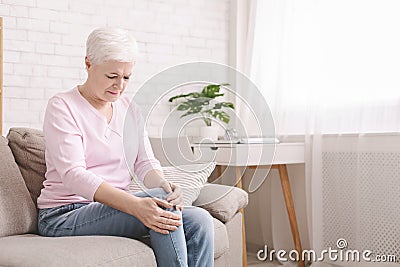 Senior woman suffering from pain in leg, massaging her knee Stock Photo