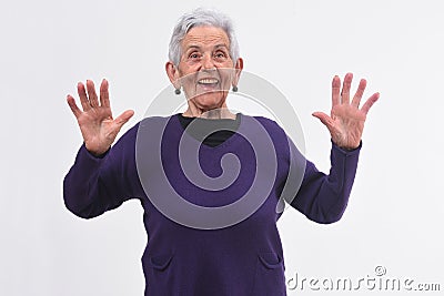 Senior woman with a surprised face and raised hands on white background Stock Photo