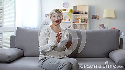 Senior woman with tablet smiling at camera, shopping online, season sales Stock Photo