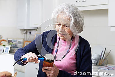 Senior Woman Taking Lid Off Jar With Kitchen Aid Stock Photo