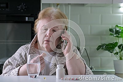 Senior woman taking pills. Female talking on mobile phone with doctor about treatment Stock Photo