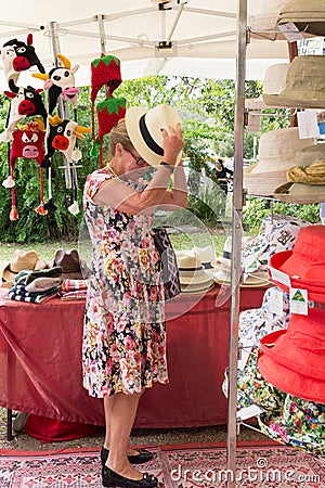 Senior woman trying on a hat at Eumundi markets, Queensland, Australia Editorial Stock Photo