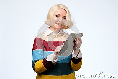 Senior woman using digital tablet surfing web media chatting online, smiling. Stock Photo