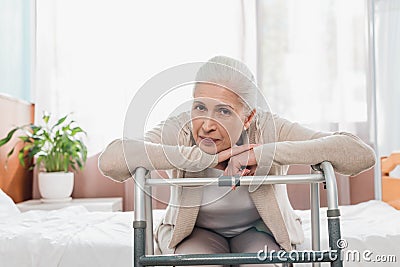 senior woman with walker looking at camera while sitting Stock Photo