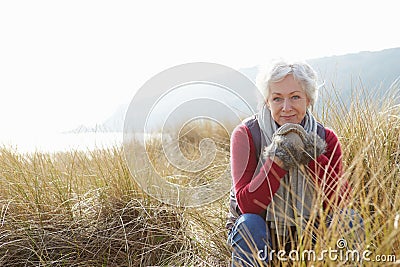 Senior Woman Walking Through Sand Dunes On Winter Beach Stock Photo