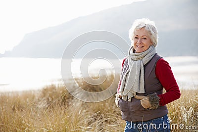 Senior Woman Walking Through Sand Dunes On Winter Beach Stock Photo